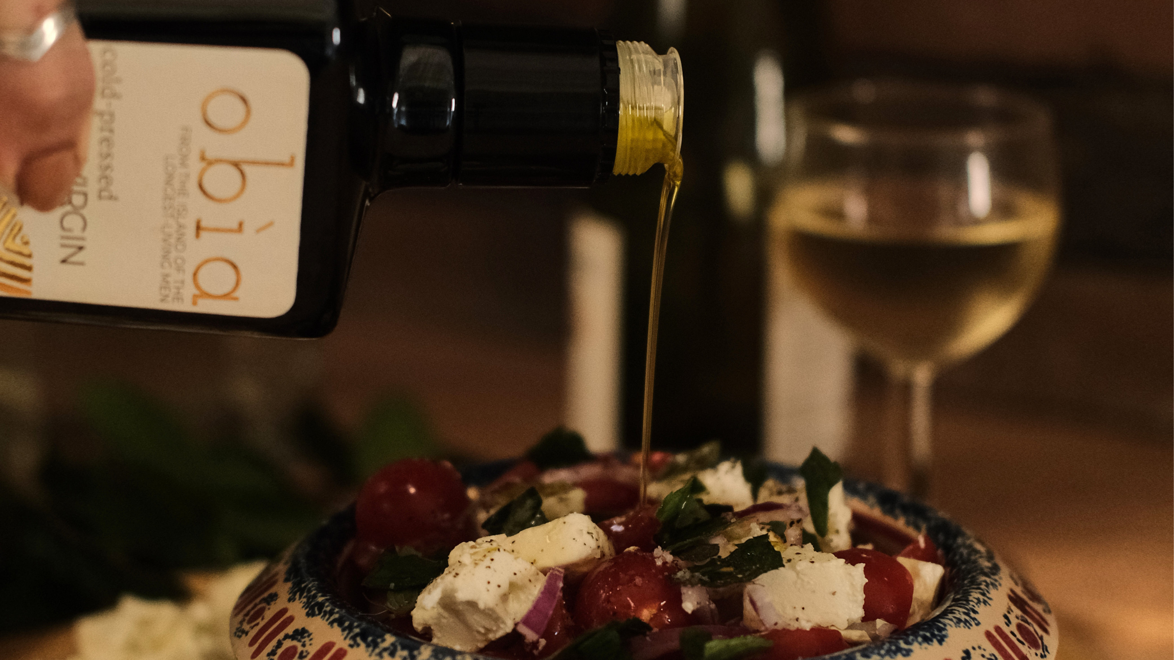 obia olive oil pouring onto mediterranean salad